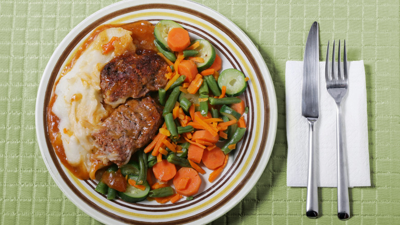Meatloaf dinner with mashed potatoes, vegetables, and silverware