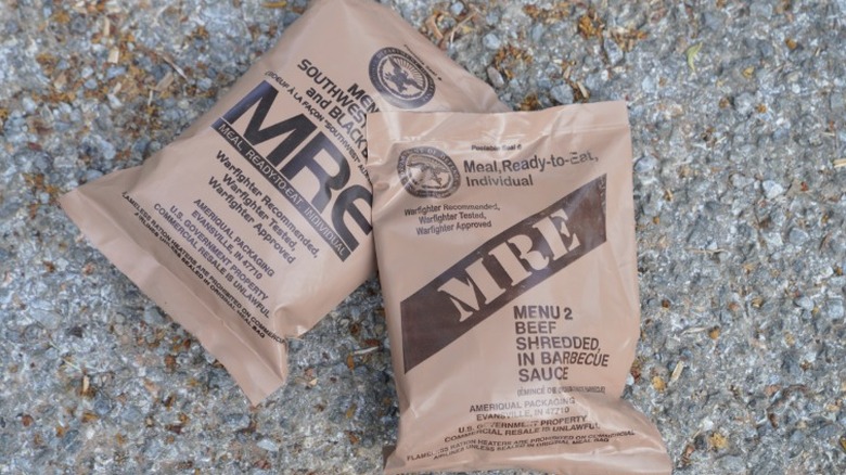 close up of two brown MRE packages on asphalt surface