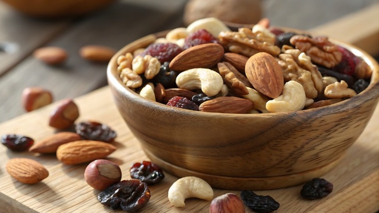 a wooden bowl of trail mix with almonds, walnuts, cashews, and raisins