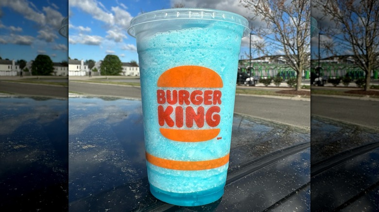 Burger King's frozen cotton candy cloud drink sits outside. Blue drink with white foam topping.