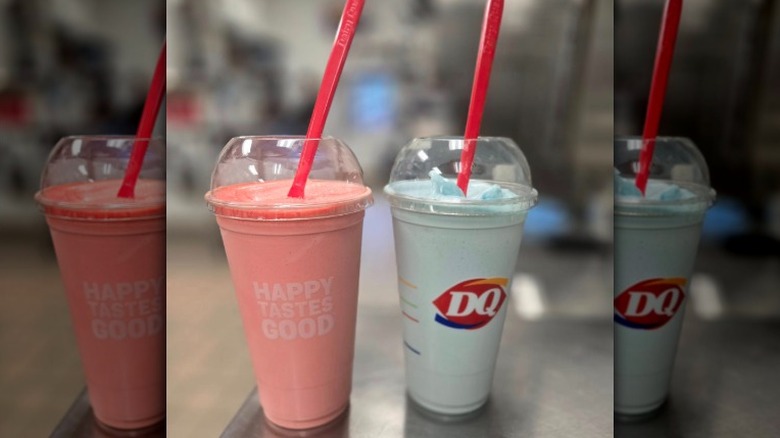 A red-colored and blue-colored Misty freeze from Dairy Queen sit on a counter