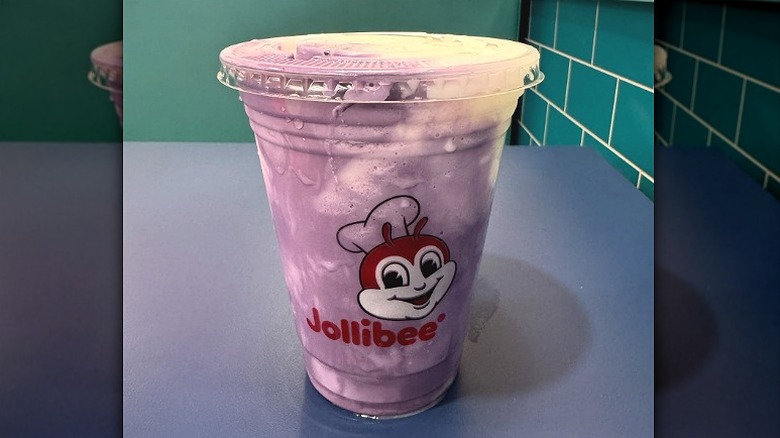 Jollibee's ube coconut freeze sits on a table. Purple and white drink.