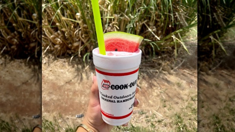 A hand holds a watermelon shake with a slice of watermelon in it from Cook Out
