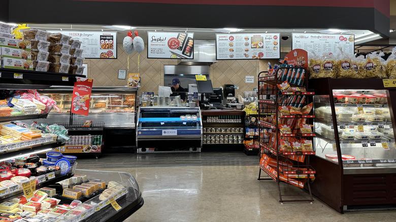 A clerk standing behind the counter of a Safeway deli.