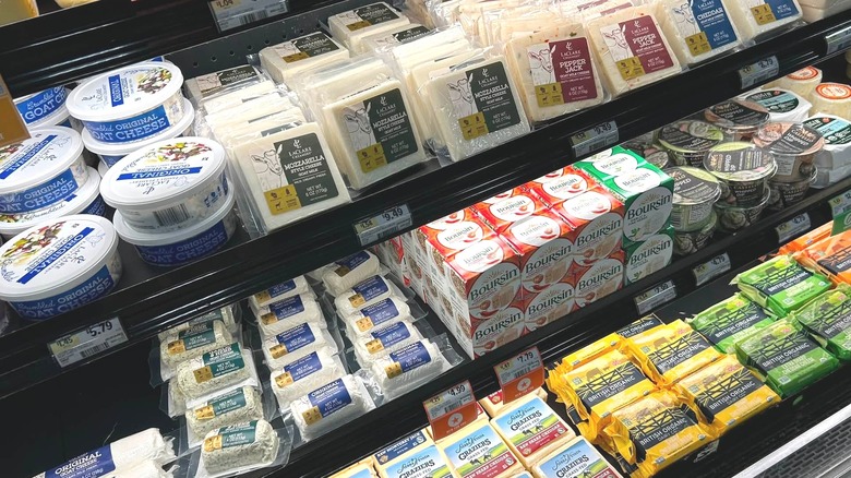 A well-lit grocery store cheese display.