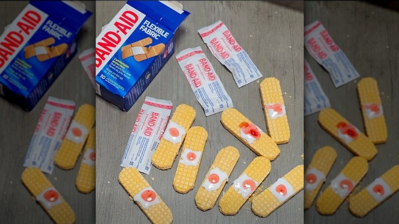 vanilla wafer cookies decorated to look like used bandages alongside a box of Band-Aid brand bandages