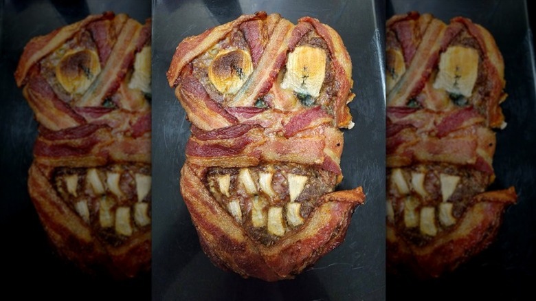 skull-shaped meatloaf wrapped in bacon with sliced onion eyes and teeth