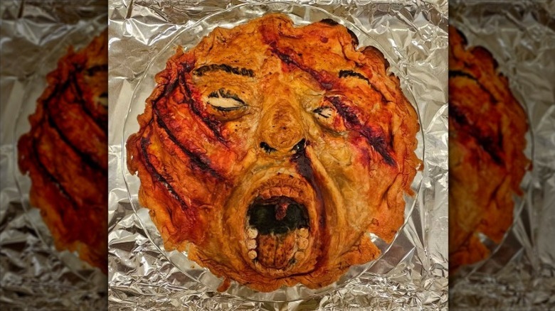 pie shaped like a screaming face in a clear pie pan sitting on crumpled aluminum foil