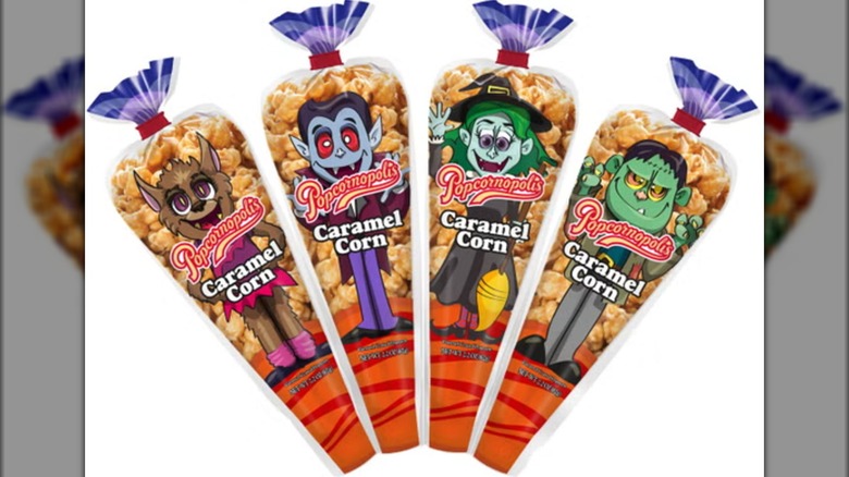 Four bags of Popcornopolis Caramel Corn Mini Cones with different cartoon monsters on front over white background
