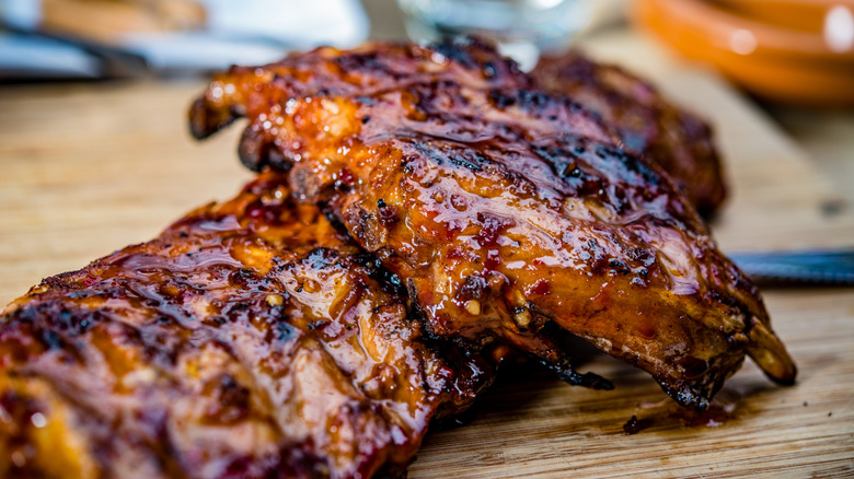 Two racks of juicy barbecue ribs on wooden cutting board