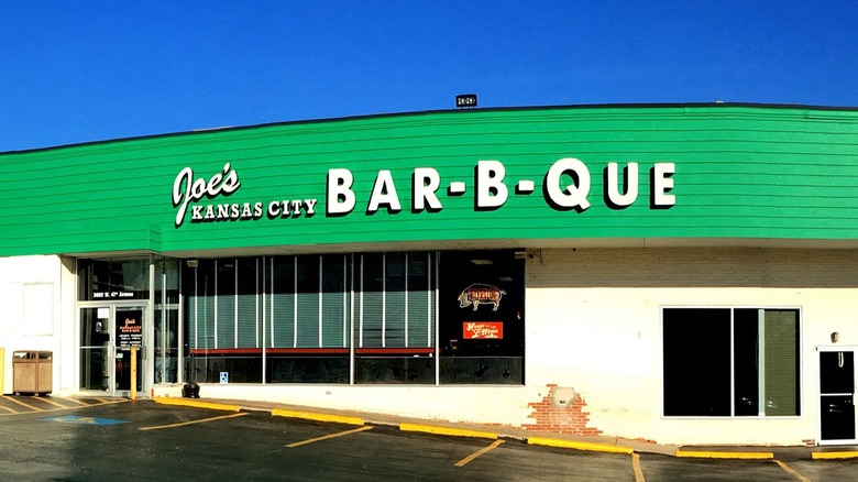 The exterior of Joe's Kansas City Bar-B-Que gas station location with parking spaces in front.
