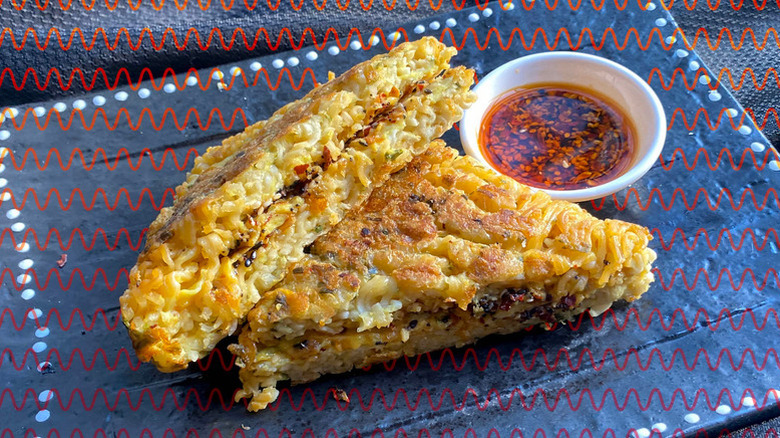 Spicy ramen grilled cheese on a platter with a side of chili sauce