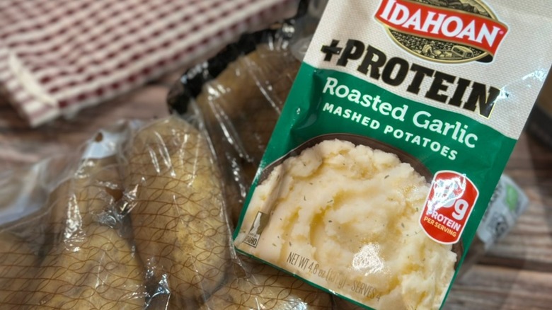 Idahoan +Protien Roasted Garlic Mashed Potatoes with sack of potatoes and red checkered towel