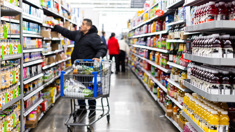 Male shopper making selection from shelf blurred out in Walmart shopping aisle