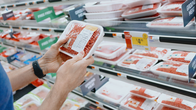 Hands holding pack of ground beef at store