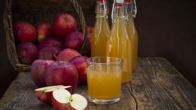 Fresh glass of apple juice next to pile of apples