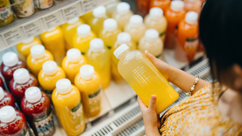 Shopper picking up bottle of juice in store