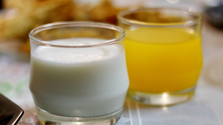Side-by-side glasses of milk and orange juice