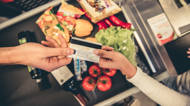 Person handing over credit card after grocery shopping