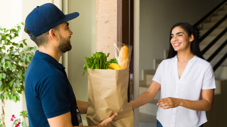 Woman smiling at man delivering her groceries to her door