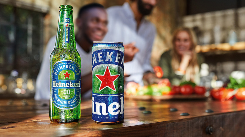 Heineken 0.0 can and bottle on a tabletop, people in background
