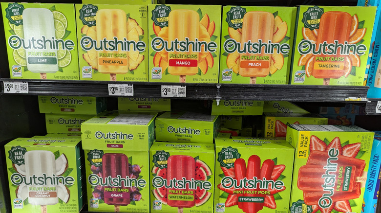 Several boxes of Outshine fruit bars on store shelves.