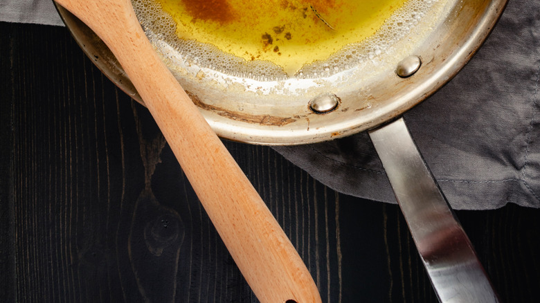 Browned butter with herb sprig in pot with wooden spoon