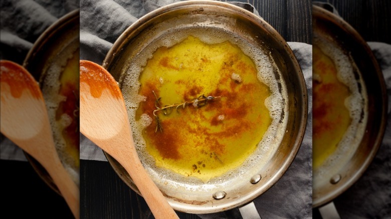Browned butter with herb sprig in pot with wooden spoon