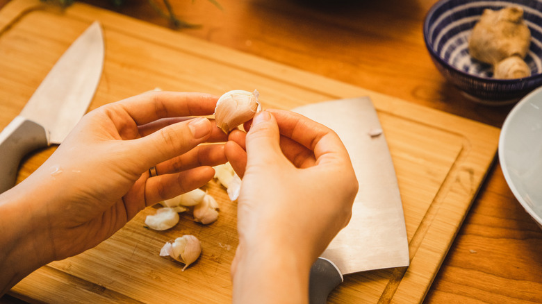 Hands of person peeling fresh garlic
