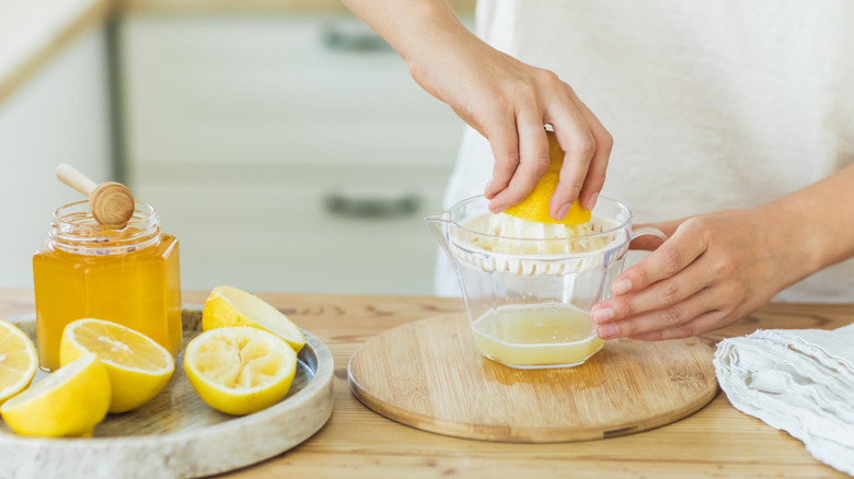 Person juicing lemons into a small glass pitcher