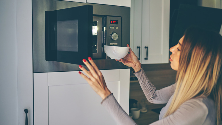 Woman placing bowl in microwave