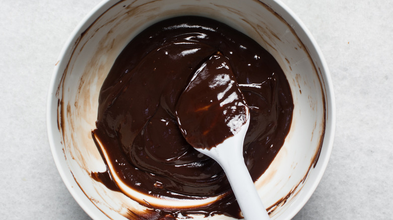 Chocolate ganache in a white bowl with a white spoon