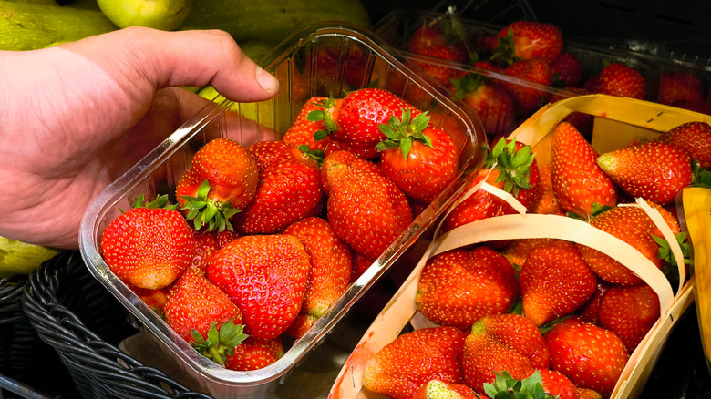 Hand picking up container of strawberries