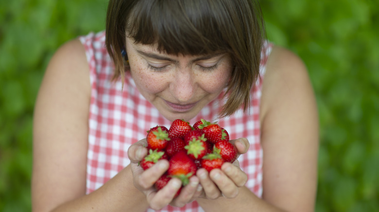 Person holding and smelling strawberries