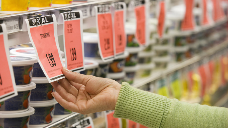 Woman touching price tag at grocery store