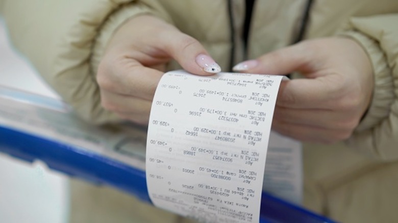 Woman holding grocery store receipt