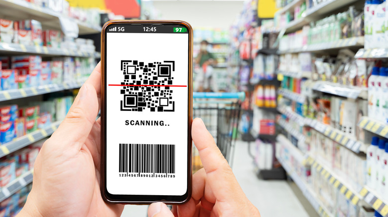 Person in grocery store holding phone with scanning app