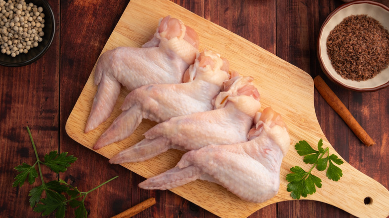 Raw chicken wings on a wooden board