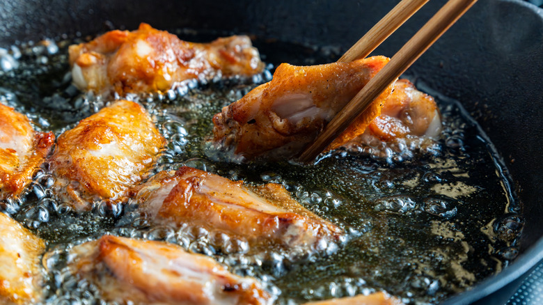 Person deep frying chicken wings