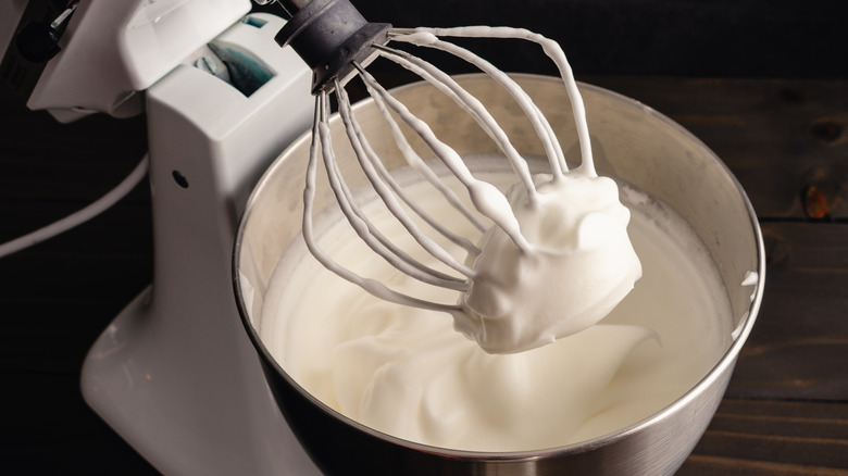 Electric mixer in the up position with stiff egg whites on the wire whisk