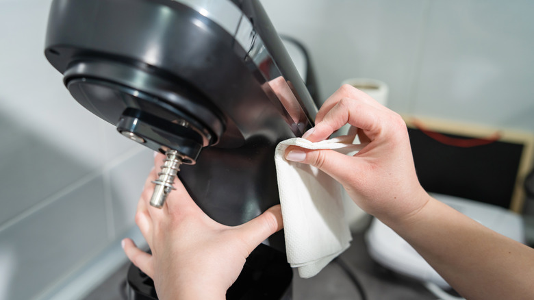 Hands wiping a stand mixer in the kitchen