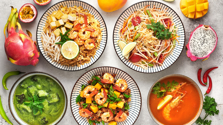 Thai dishes on a table including Tom yum, Pad Thai, Som Tum, Green curry, and fried rice