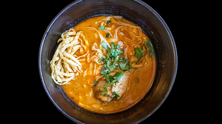 Khao Soi noodle soup in a black bowl