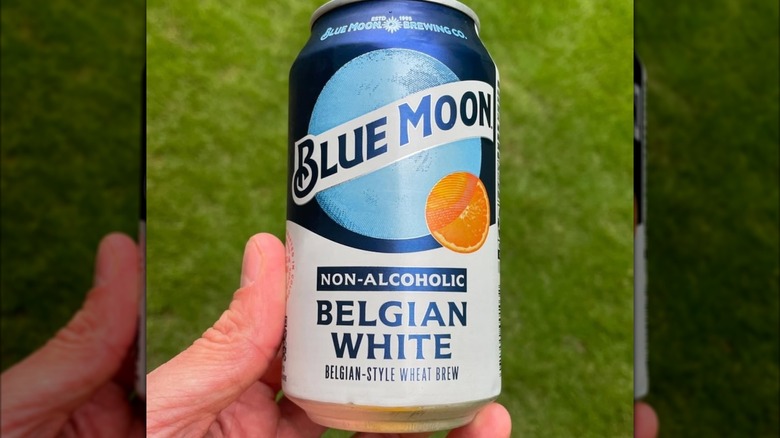 A hand holding can of Blue Moon Non-Alcoholic Belgian White