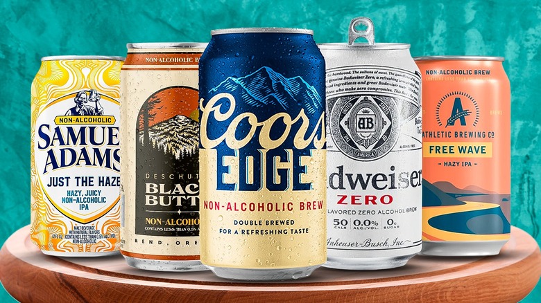 Various brands of nonalcoholic beer cans on a wooden stool