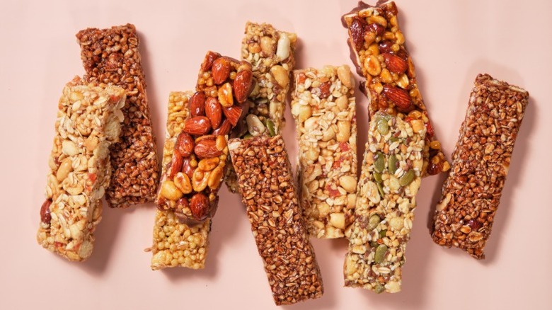 A selection of energy bars with different nuts and seeds on a pink background