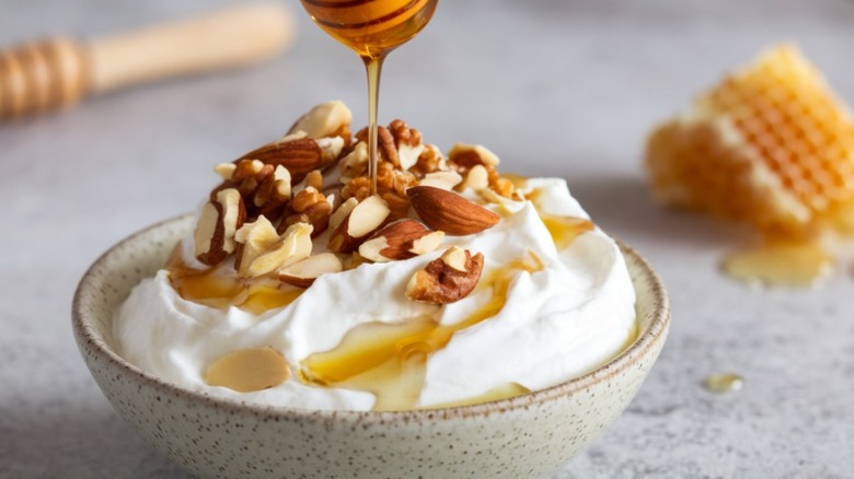 A bowl of greek yogurt topped with honey, walnuts, and almonds
