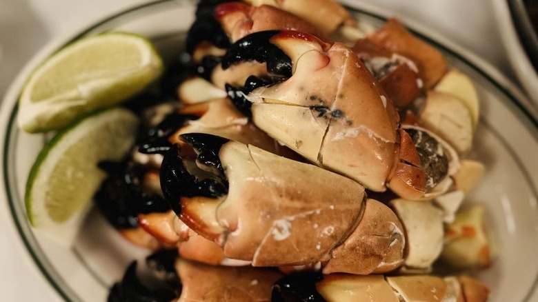 Pile of cracked stone crab claws ona plate with lime wedges