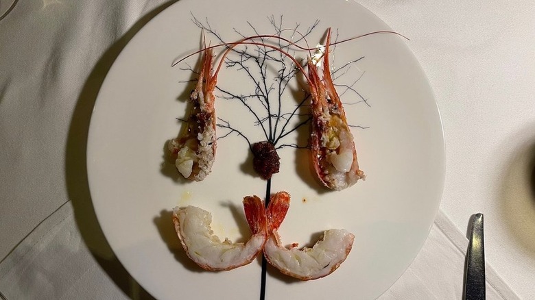 Prawns on a white plate with a spindly tree design