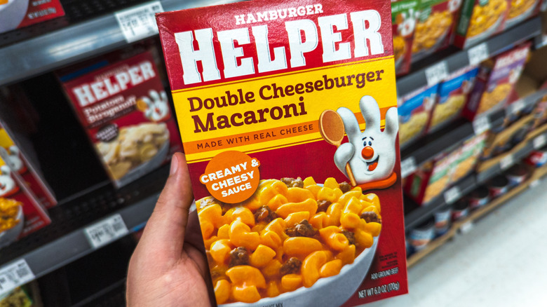 A hand holding a box of Hamburger Helper